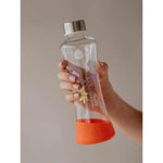 Farbenfroh Glastrinkflasche im ergonomischem Design mit Blumenprint in orange, gelb und flieder. Mit orangem Silikonboden als Schutz und gegen das Rutschen.