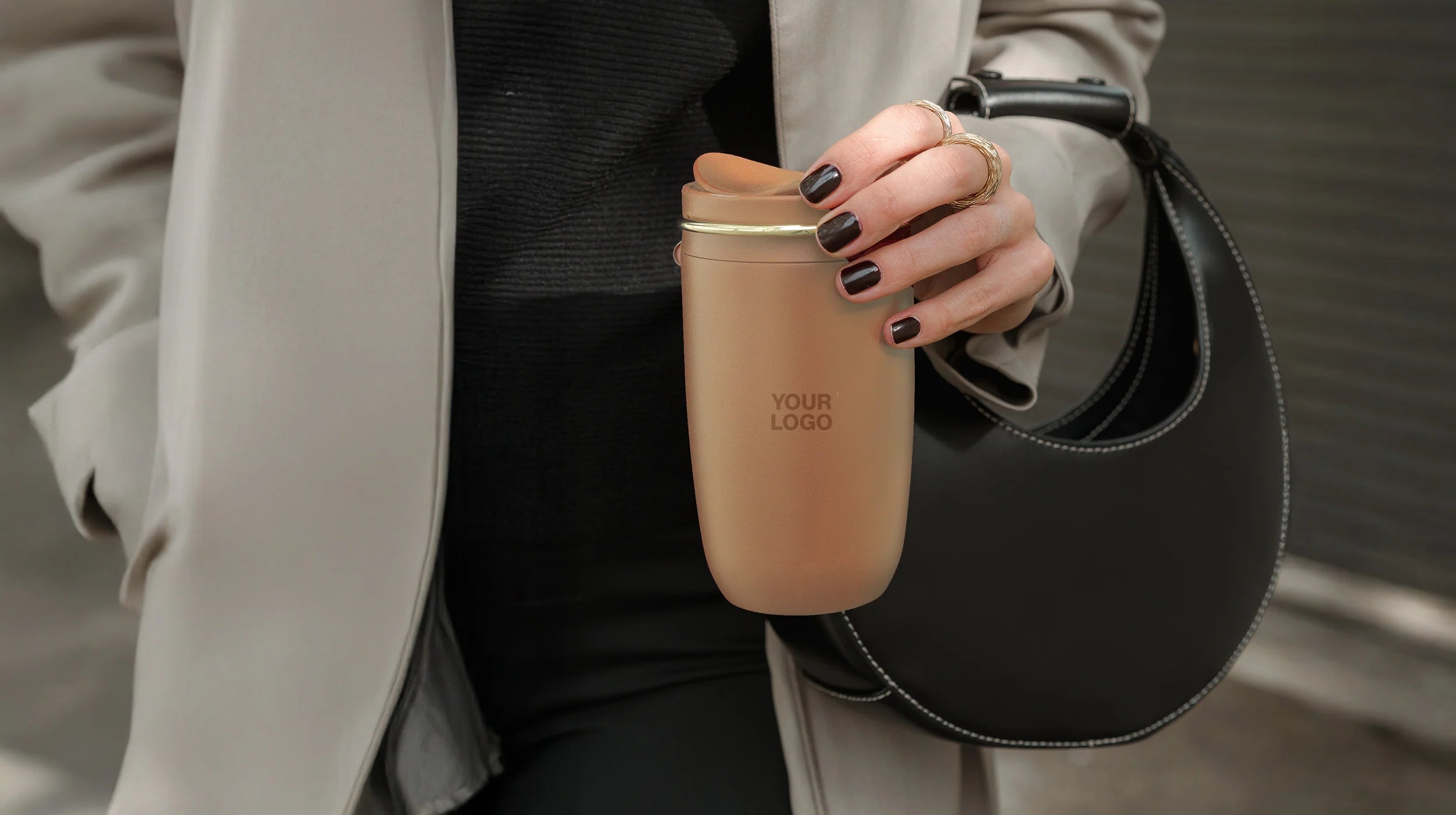 Person hält einen personalisierten matten EQUA Thermo-Cup Kaffeebecher in Toffee-Braun mit "YOUR LOGO" Gravur als Beispiel für Corporate Co-Branding.