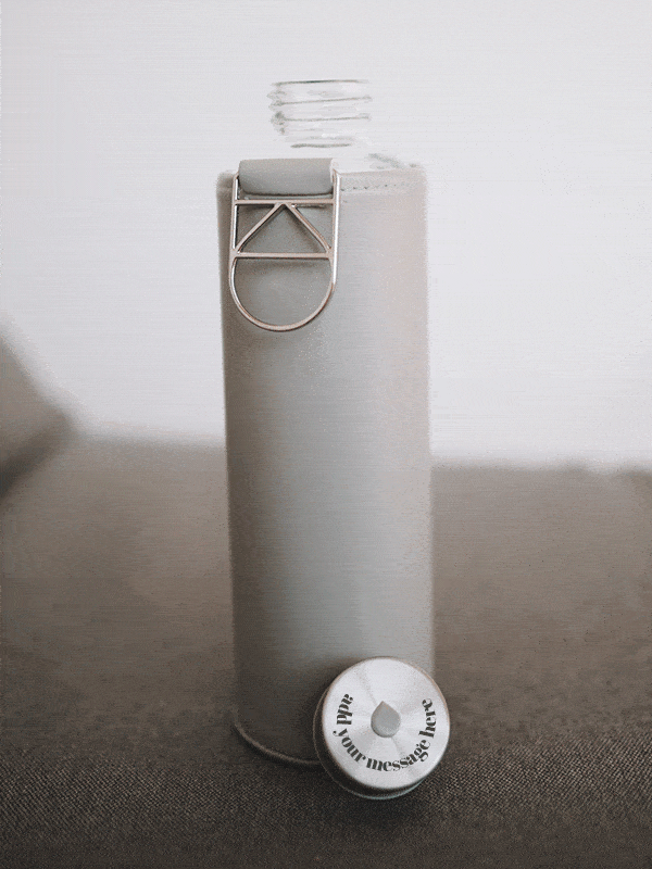 Glastrinkflasche kann ergänzt werden mit zahlreichen passenden Schutzhüllen aus faux-leather oder Filz. Schützt die Glasflasche auch für den Gebrauch unterwegs. Diese kommt mit einer grauen Hülle. Deckel kann graviert werden mit Ihrer Message wie auf dem Bild.