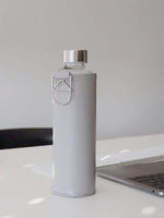 Wasserflasche aus hitzebeständigem Borosilikatglas mit hellgrauer Hülle als Schutz für unterwegs. Hergestellt in Europa. Geschmacksneutral - kein Plastikgeschmack - keine Edelstahlgeschmack.