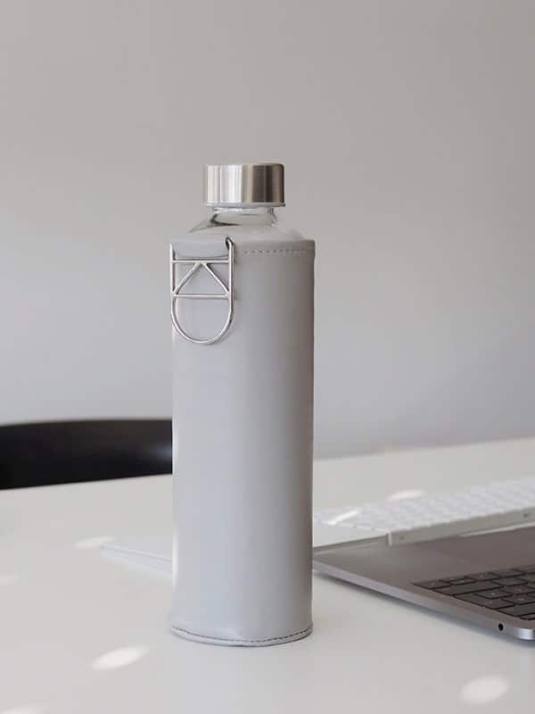 Wasserflasche aus hitzebeständigem Borosilikatglas mit hellgrauer Hülle als Schutz für unterwegs. Hergestellt in Europa. Geschmacksneutral - kein Plastikgeschmack - keine Edelstahlgeschmack.
