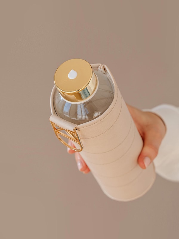 Stylishe Trinkflasche aus Glas mit beiger Hülle.