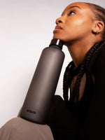 Stylishe minimalistische schwarze Trinklflasche aus hitzebeständigem Borosilikatglas. Angenehme haptik - schwarz matte Oberfläche.