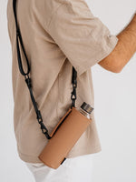 Dank dem Tragegurt der an der beigen faux-leather Schutzhülle befestigt ist kann die Crossbody Glastrinkflasche wie eine Tasche getragen werden. So bleiben die Hände frei. Praktisch für unterwegs.