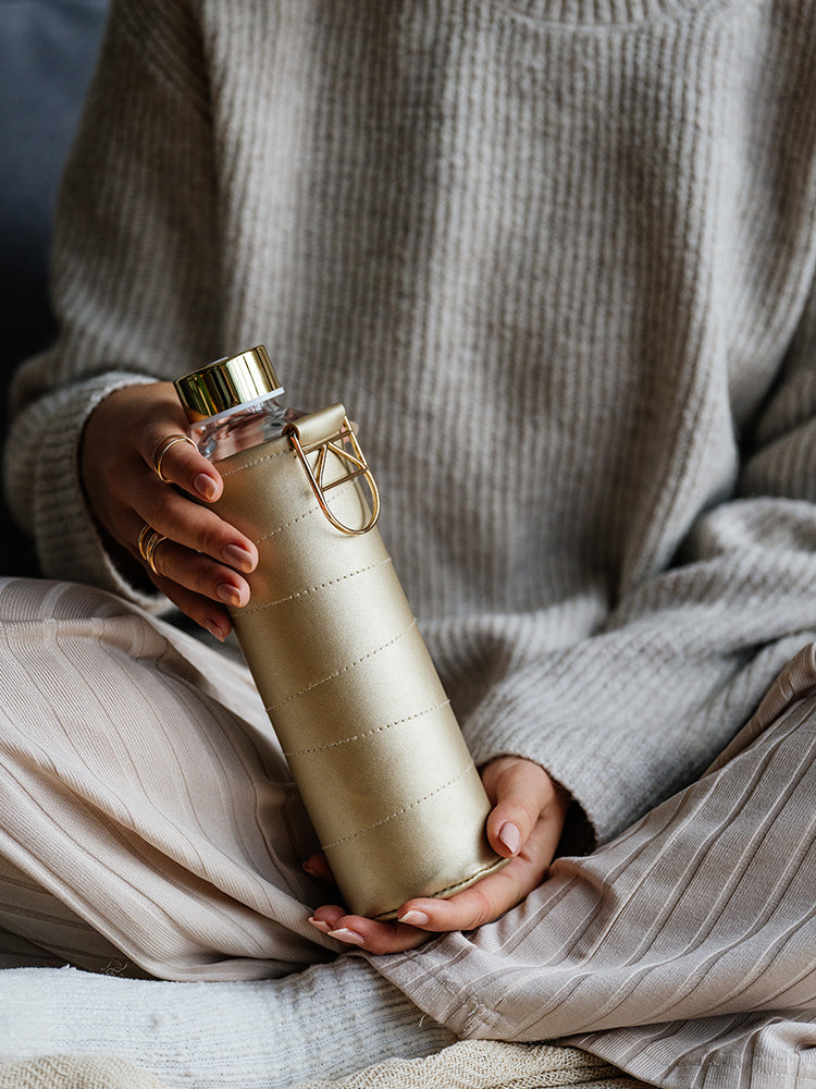 Glastrinkflasche kann ergänzt werden mit zahlreichen passenden Schutzhüllen aus faux-leather oder Filz. Schützt die Glasflasche auch für den Gebrauch unterwegs. Diese Glaswasserflasche kommt in einer hell goldnene Hülle - chic und gut kombinierbar.